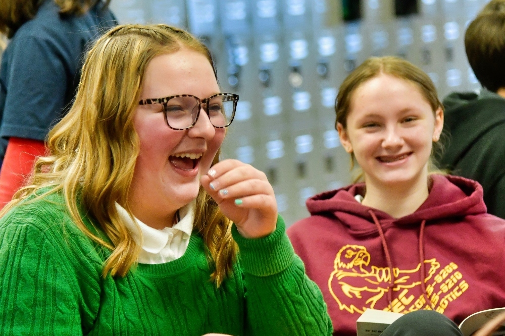Two JPEC students are sitting at a table and laughing.