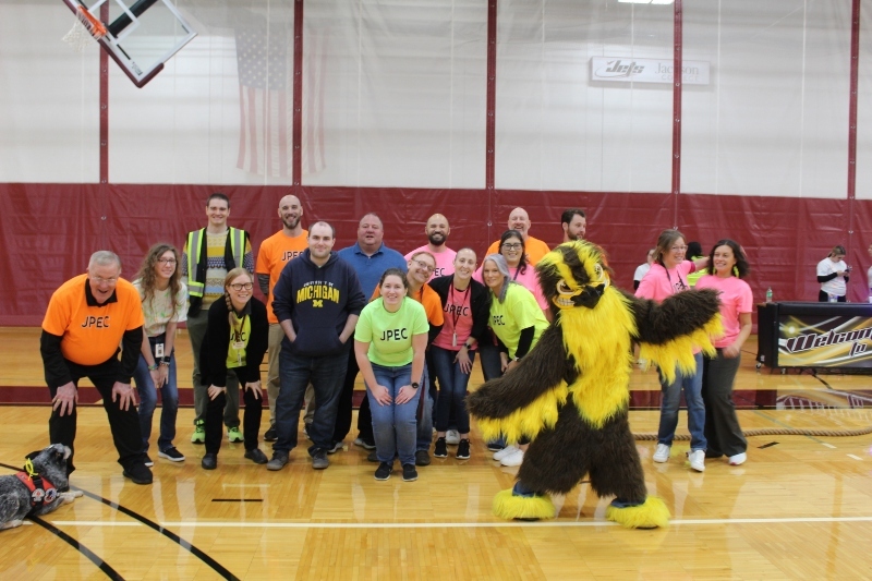 Teachers and staff from Jackson Preparatory & Early College and the school mascot, the Falcon, pose together in the Jackson College gym