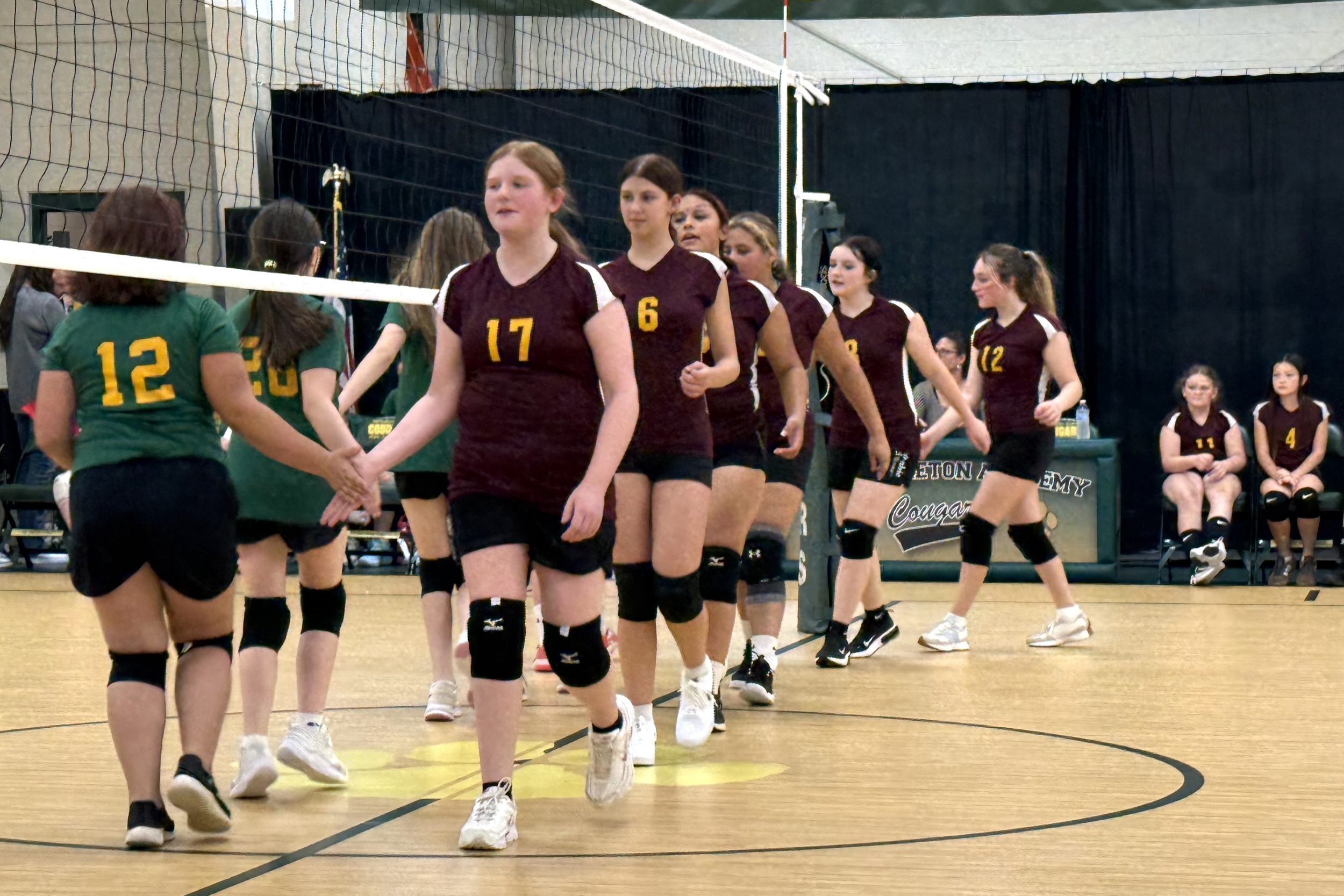 JPEC volleyball team on the court slapping hands with competitors