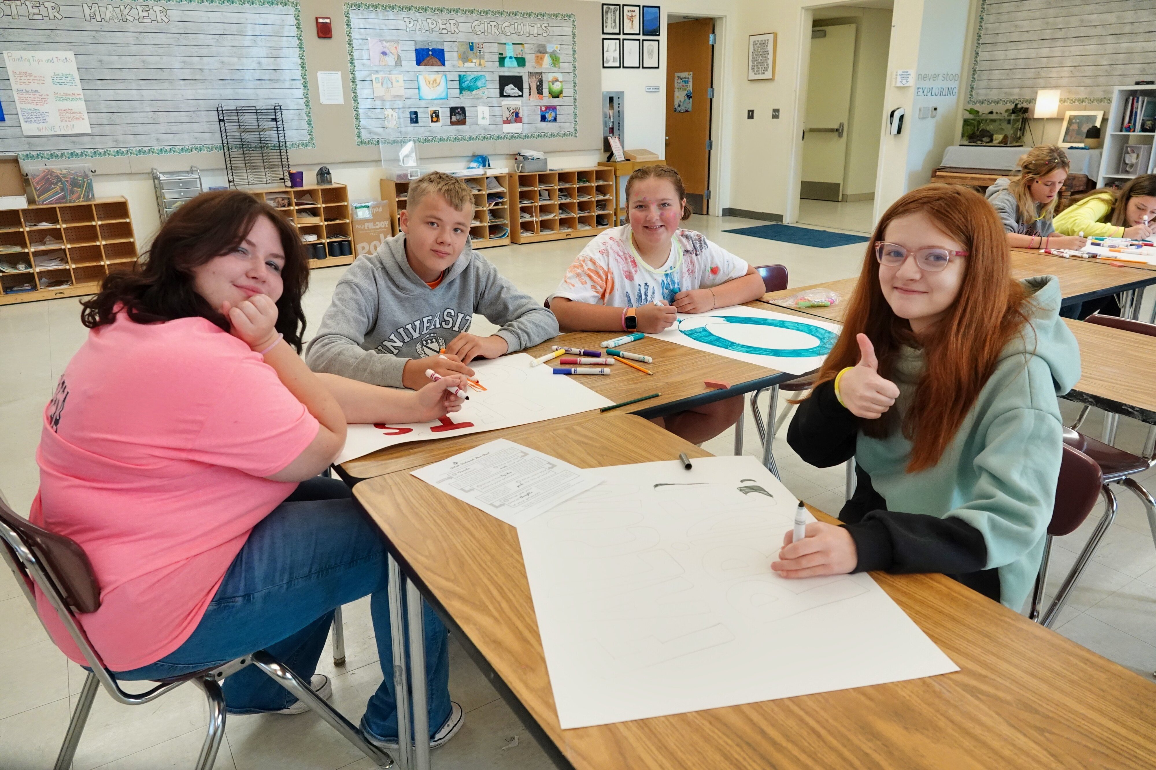 4 Jackson Preparatory & Early College students sit at a table designing posters.